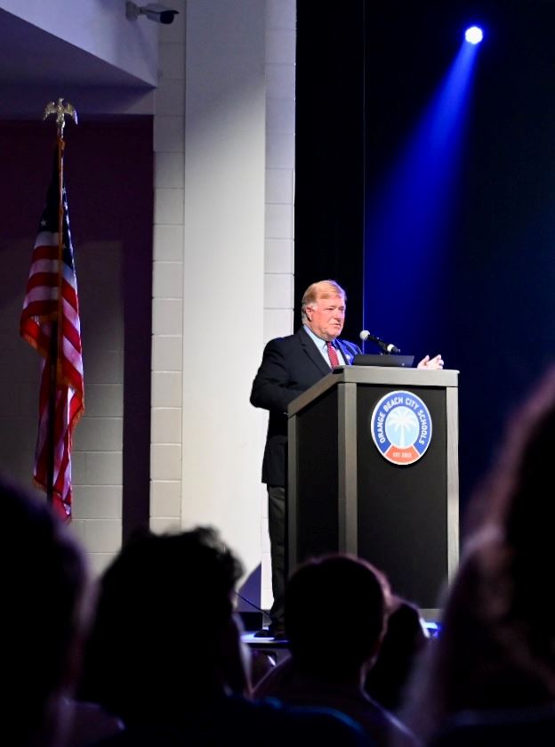 Man at podium on stage of the Orange Beach Performing Arts Center